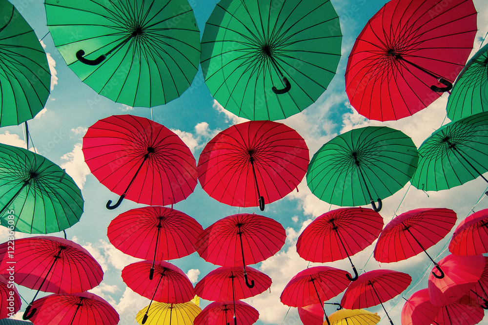 colorful green , red and yellow umbrellas under the beautiful cloudy sky