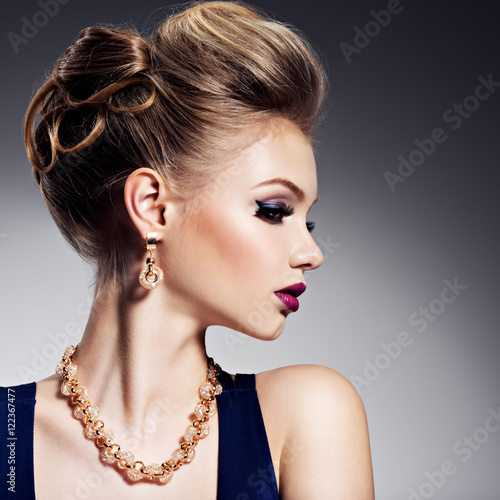Beautiful woman with style hairstyle and gold jewelry with brig