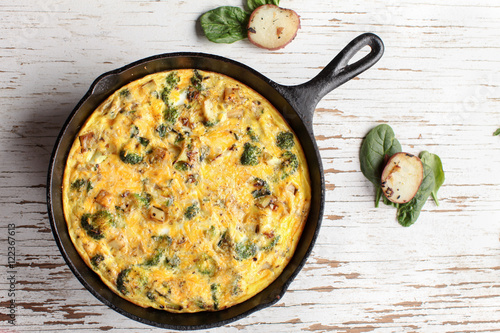 Baked egg frittata with spinach, cheese, broccoli, red potatoes, bacon, milk, and spinach far away shot from top photo