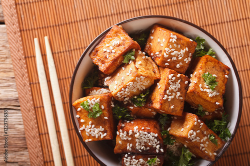 Stir fry tofu with sesame seeds and herbs close-up. horizontal top view photo