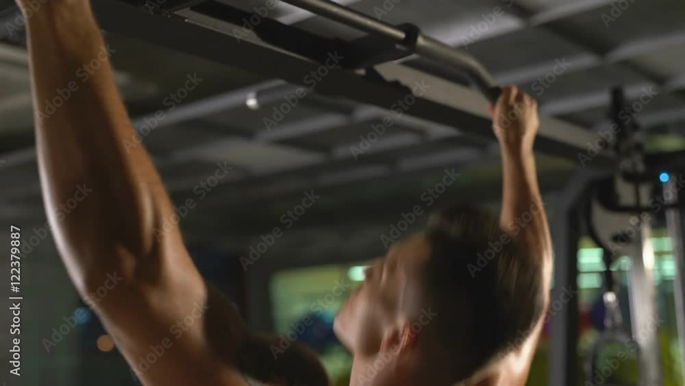 At gym. View of sweaty guy pulling up on crossbeam At gym. View of sweaty guy pulling up on crossbeam