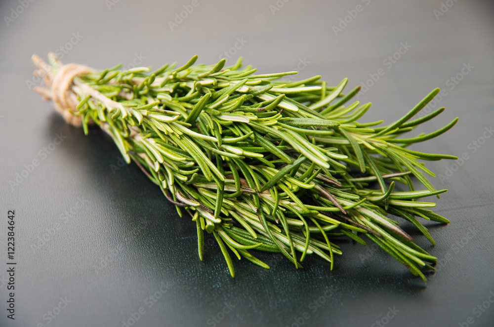 Sprigs of rosemary tied with string on a dark gray background.