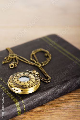 Pocket watch and book against a rustic background