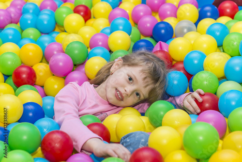Happy children playing and having fun at kindergarten with colorful balls, a child in the pool with balls.