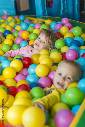 Happy children playing and having fun at kindergarten with colorful balls, a child in the pool with balls.