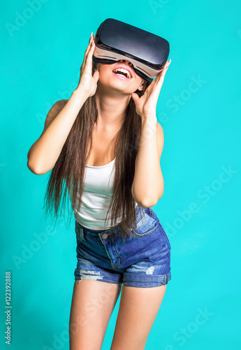 Sexy young girl with glasses of virtual reality on a blue background.