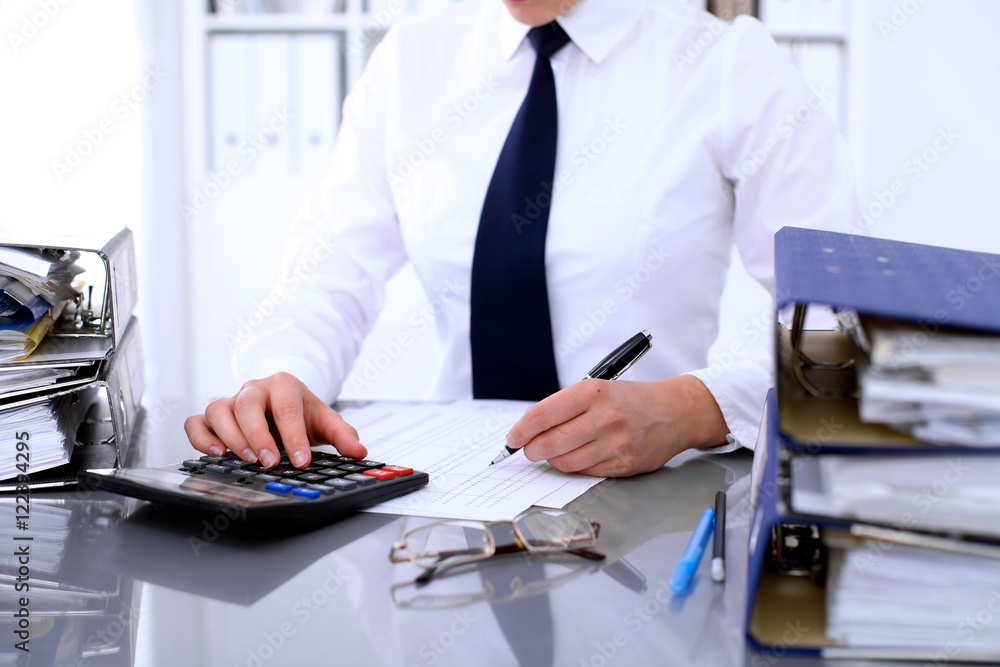 Fototapeta premium Bookkeeper or female financial inspector making report, calculating or checking balance. Internal Revenue Service checking financial document. Audit concept.