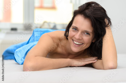 Friendly happy young woman lying on her bed