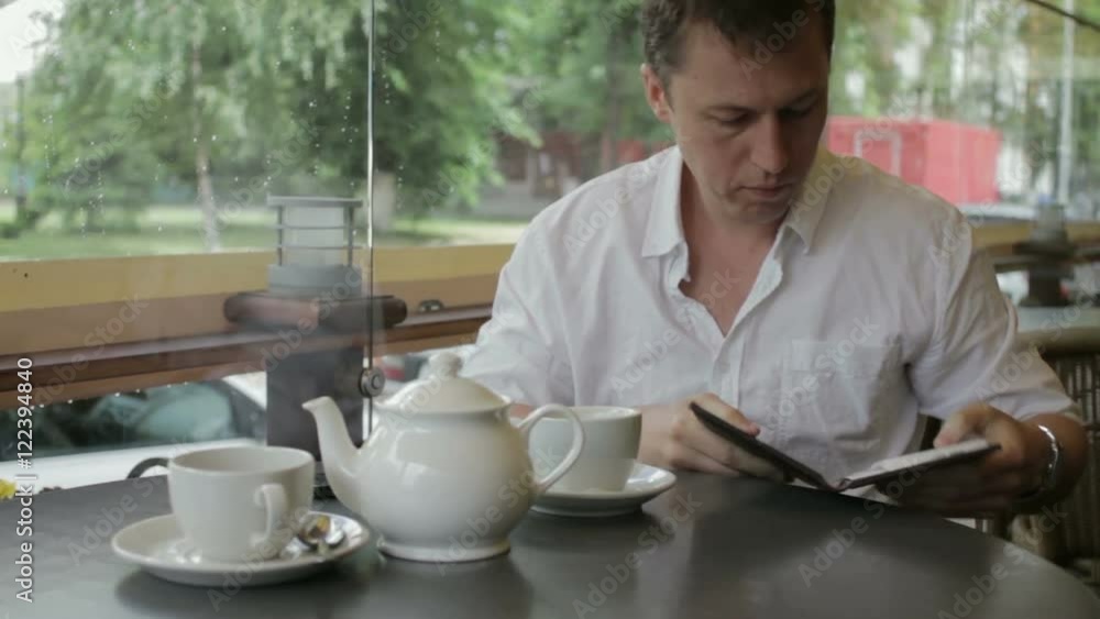 A greedy man pays the bill in a summer cafe and changes his mind at the last moment to leave a tip. A greedy man pays the bill in a summer cafe and changes his mind at the last moment to leave a tip.