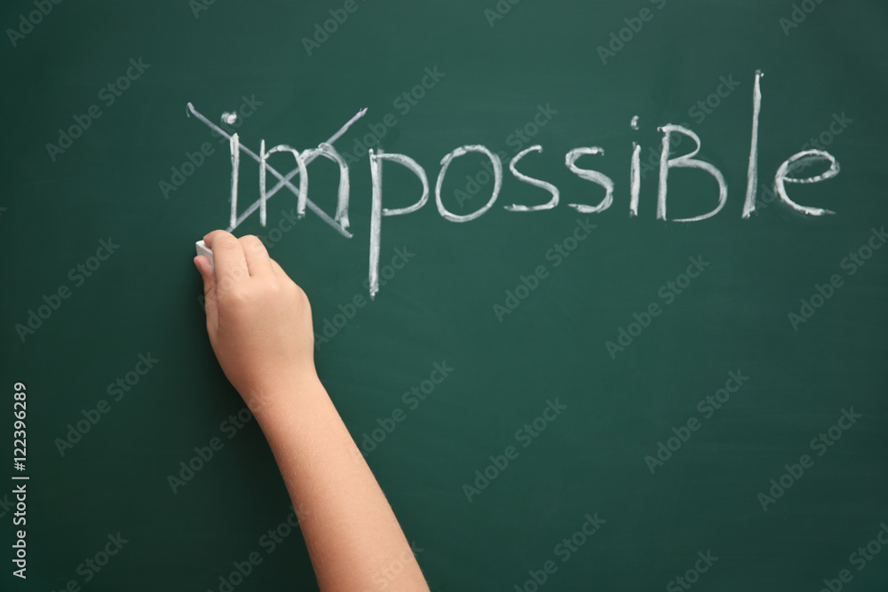 Schoolboy putting a cross over word impossible on blackboard Schoolboy putting a cross over word impossible on blackboard