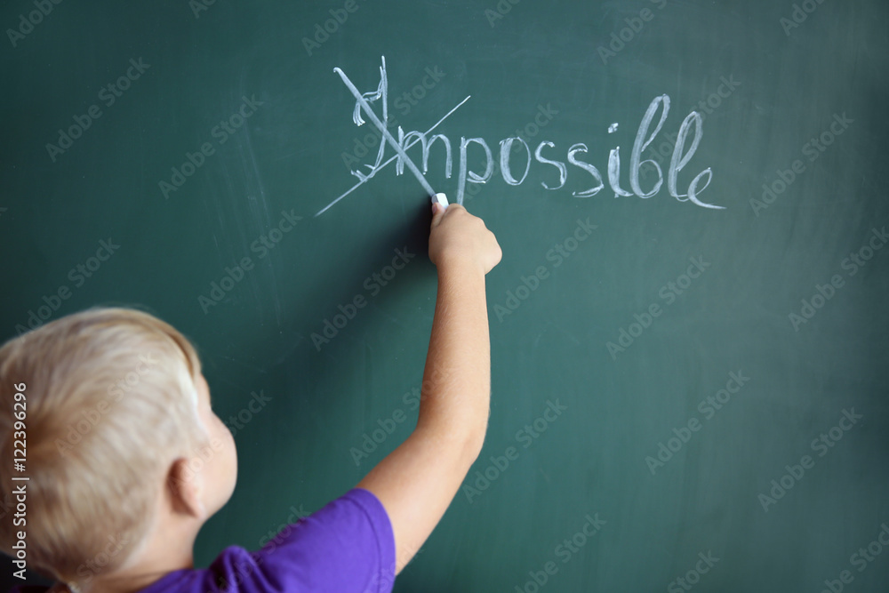 Schoolboy putting a cross over word impossible on blackboard Schoolboy putting a cross over word impossible on blackboard
