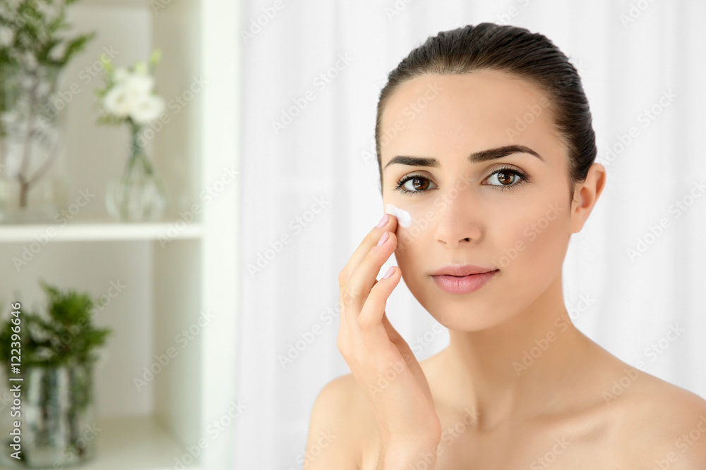 Portrait of young woman applying facial cream Portrait of young woman applying facial cream