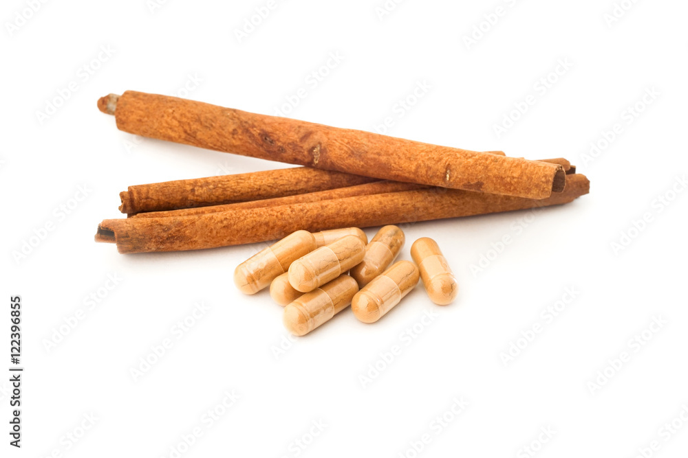 herbal powder in capsule and cinnamon on white background herbal powder in capsule and cinnamon on white background