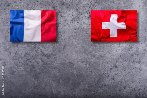 Flags of the france and switzerland on concrete background. photo