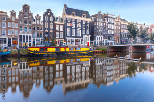 Amsterdam canal Singel with typical dutch houses, bridge and houseboats during morning blue hour, Holland, Netherlands.