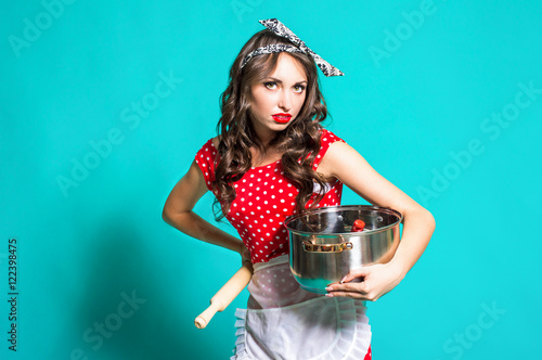 Sexy young housewife in a red dress holding a pot.
