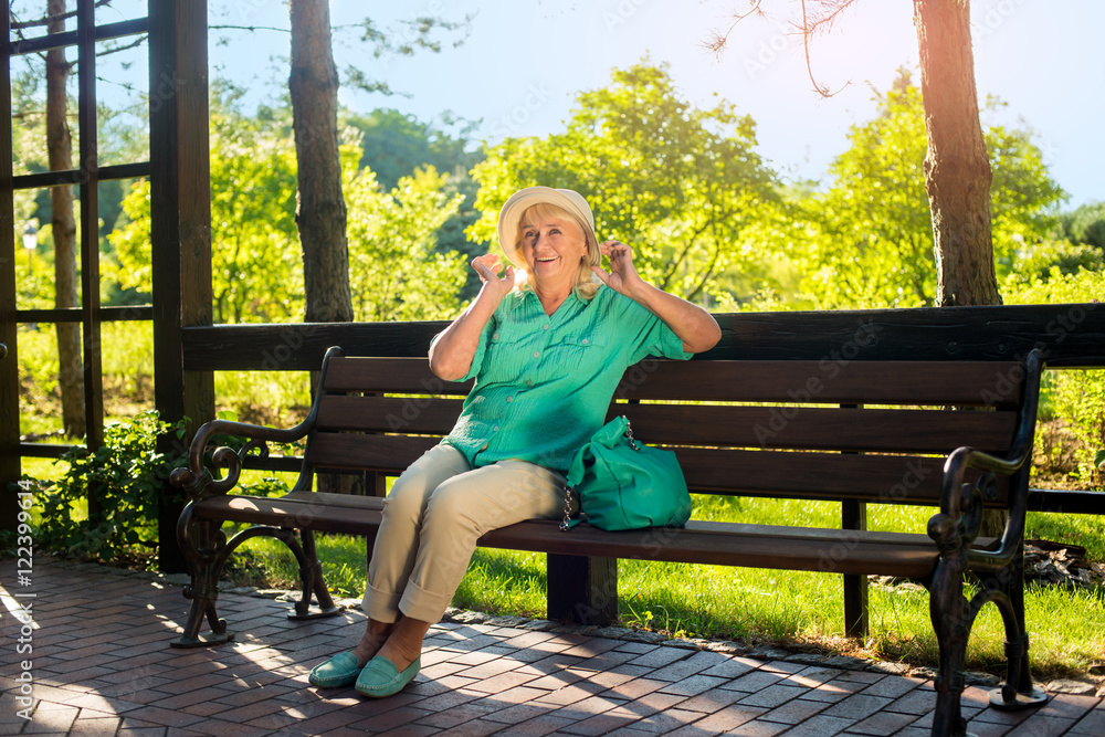 Senior woman smiling. Mature lady on park bench. Sunny days of August. Enjoying rest in fresh air. Senior woman smiling. Mature lady on park bench. Sunny days of August. Enjoying rest in fresh air.