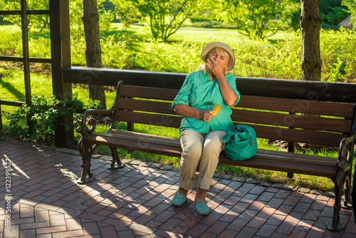 Mature woman eating pills. Lady sitting on park bench. Medicine prescribed by the doctor. Quickly recover from illness.