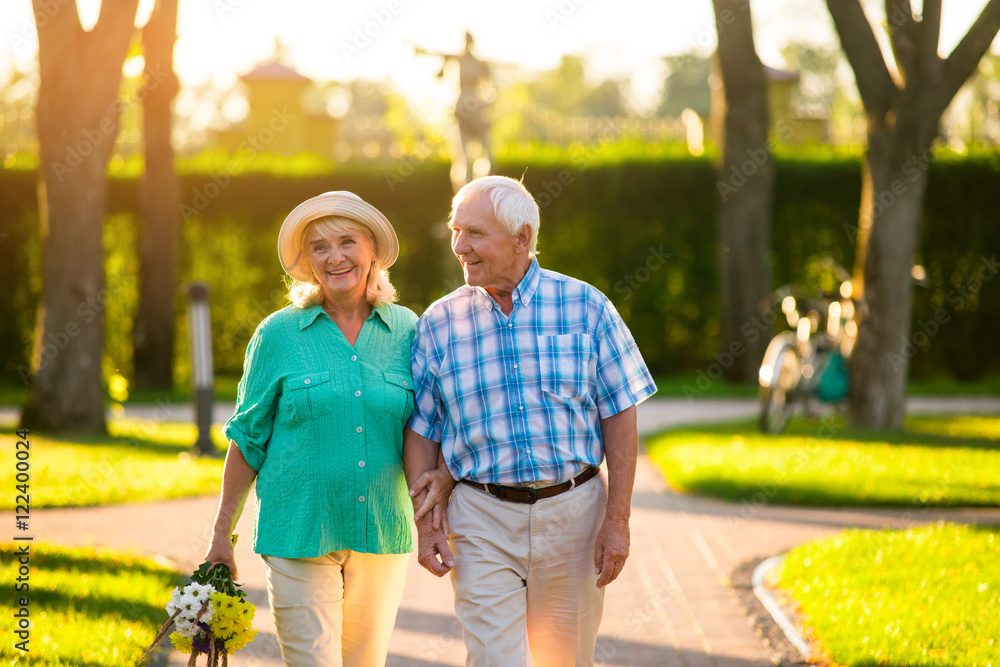 Naklejka premium Elderly couple on nature background. Man and woman with bouquet. Love tested by time. Stay devoted and honest.