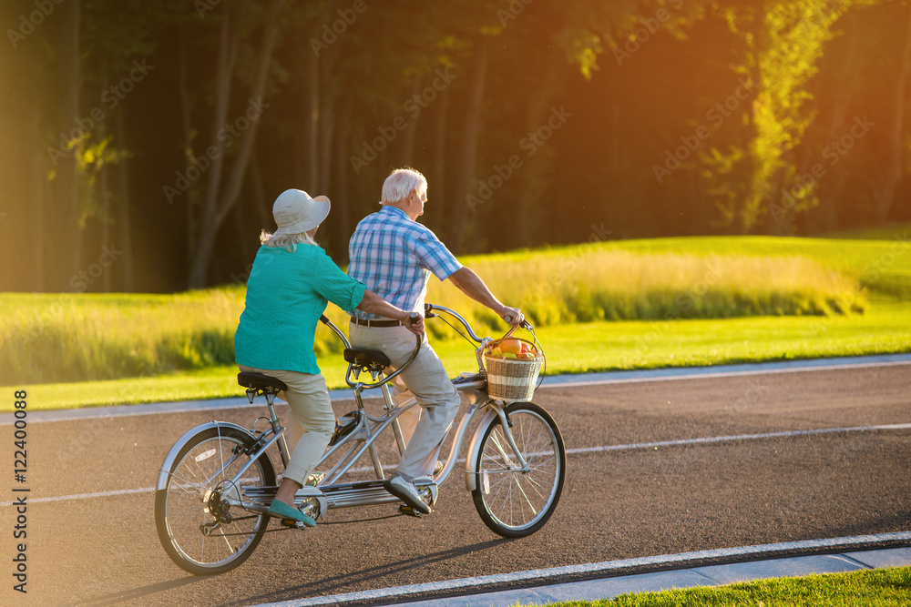 Naklejka premium Senior couple on tandem bicycle. Bike on the road. Faster than wind. The racer inside me.
