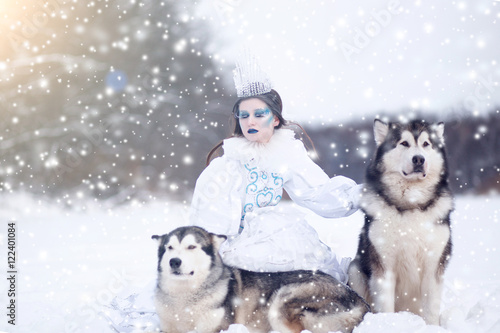 Snow-queen. Fairy tale girl with Huskies or Malamute. Beautiful snow queen witn dogs. Christmas. photo