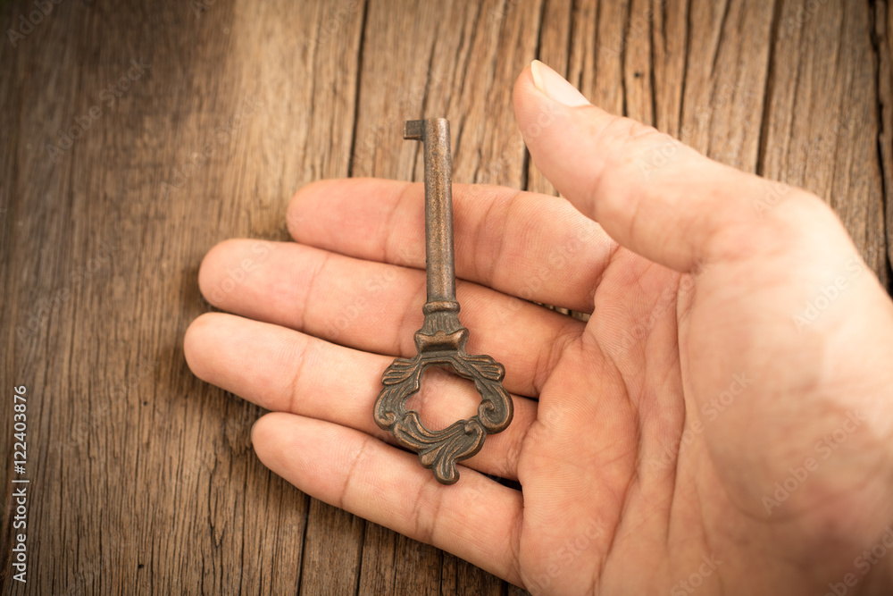 Key in hand with old wooden background, Selective focus.