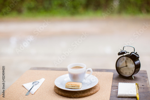 Coffee cup with sweets on the table with brown paper notes with a pen nearby.