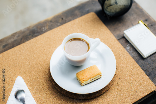 Cup of coffee with dessert on the table with brown and pads.