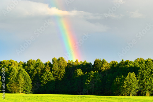 Rural landscape with beautiful rainbow after summer rainstorm over the forest. Woznawies, Podlaskie province, north-eastern Poland. photo