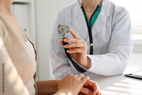Doctor with a stethoscope in the hand. Physician examines her female patient. © rogerphoto