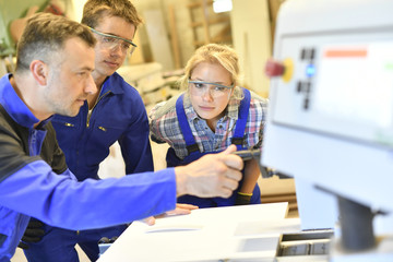 Professional teacher showing carpentry machinery to students