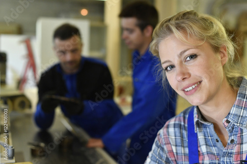 Portrait of young woman apprentice in workshop