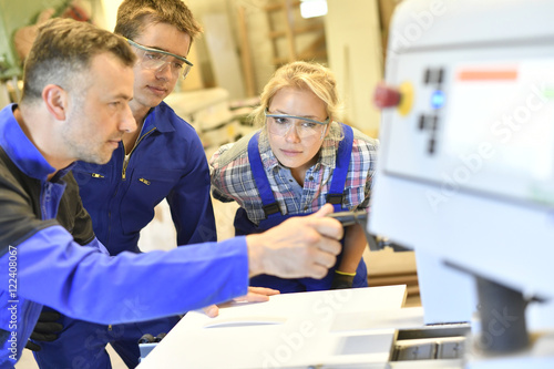 Tableau sur toile Professional teacher showing carpentry machinery to students