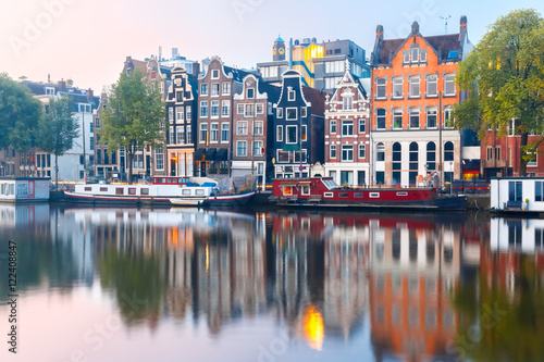 Amsterdam canal Amstel with typical dutch houses and boats during sunrise  Holland  Netherlands.