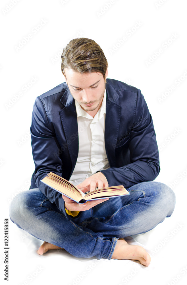 Attractive young man reading or studying on the floor, isolated on white Attractive young man reading or studying on the floor, isolated on white