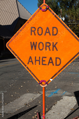 Road work ahead orange diamond sign on a crosswalk