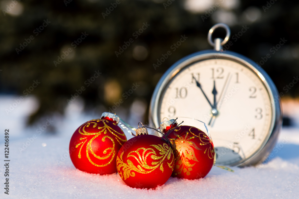 Three red christmas balls and watch on a snow.