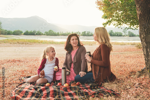 Caucasian mother and her two daughter together have a picnik in the park