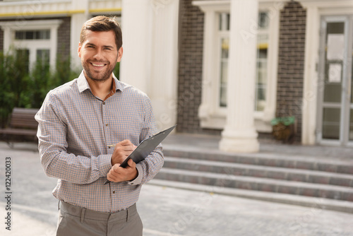фотографія Smiling realtor standing outside modern house
