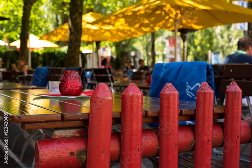 Biergarten im Sommer mit roten Zaun und gelben Schirmen