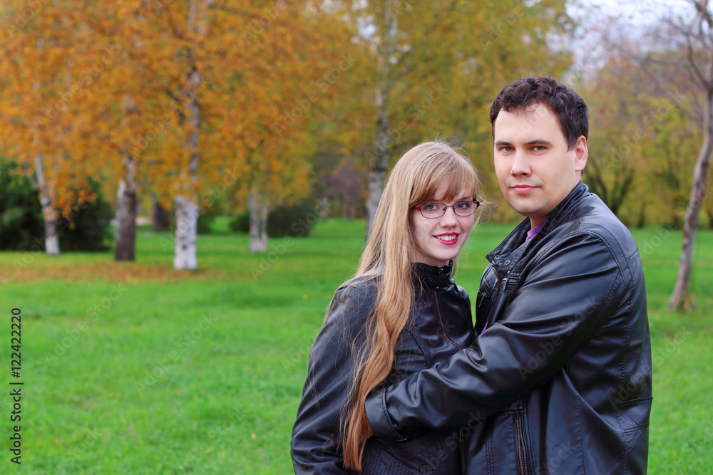 Fototapeta premium Man embraces woman in black leather jackets in autumn park