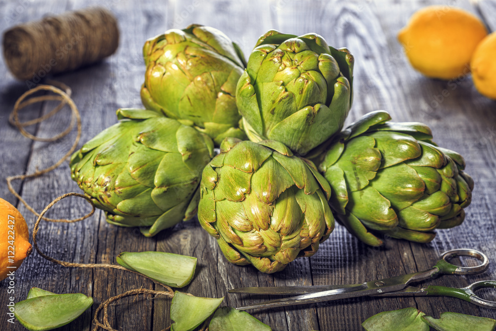 Fototapeta premium Ripe organic artichokes on the rustic wooden board.