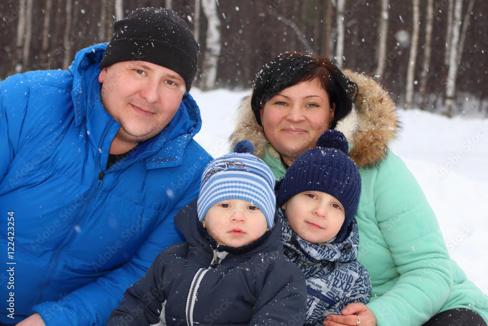 Happy family (father, mother, two sons) pose in winter day durin Happy family (father, mother, two sons) pose in winter day durin