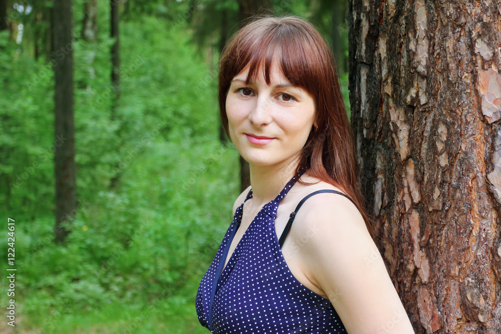 Pretty woman poses near tree in green summer forest at sunny day Pretty woman poses near tree in green summer forest at sunny day