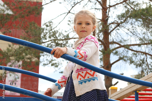 Little beautiful girl plays on children playground in sunny summ © singulyarra