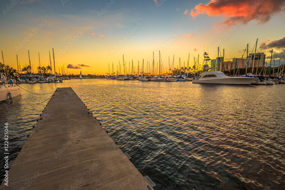 Wooden jetty in Ala Wai Harbor at sunset. Ala Wai Harbor is the largest small-boat and yacht harbor in Hawaii, situated between Waikiki and downtown Honolulu in Oahu Island, Hawaii, United States.