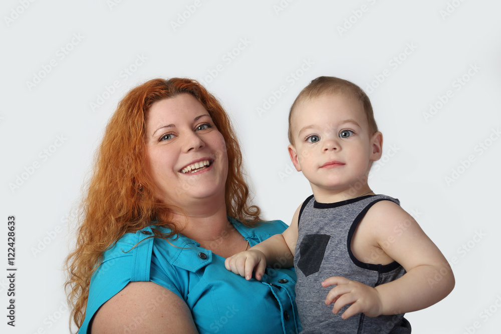 Happy redhead woman with her little son on hands on gray background Happy redhead woman with her little son on hands on gray background