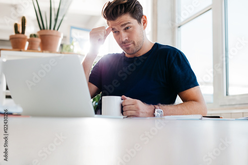 Thoughtful young man sitting at his workplace in office