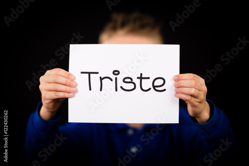 Child holding sign with Spanish word Triste - Sorry