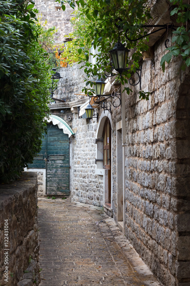 The narrow street in the stone fortress with lanterns on a wall